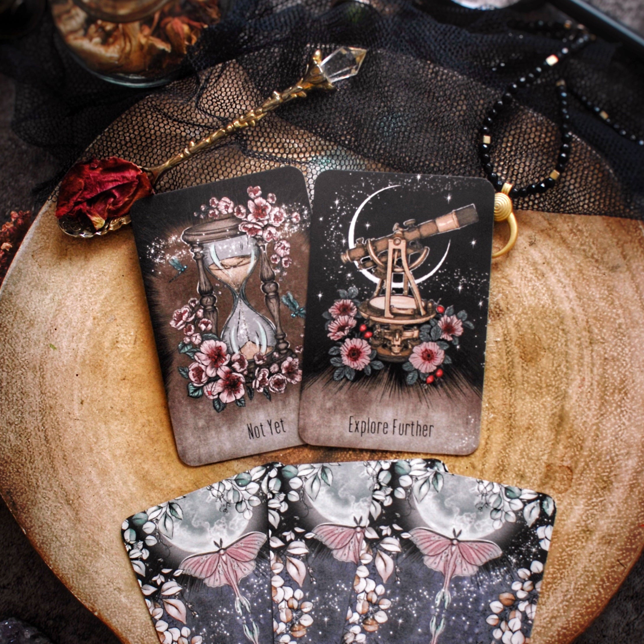 Three tarot cards with decorative designs on a wooden surface.