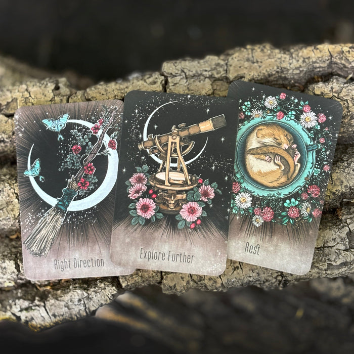 Three tarot cards with celestial designs on a wooden surface