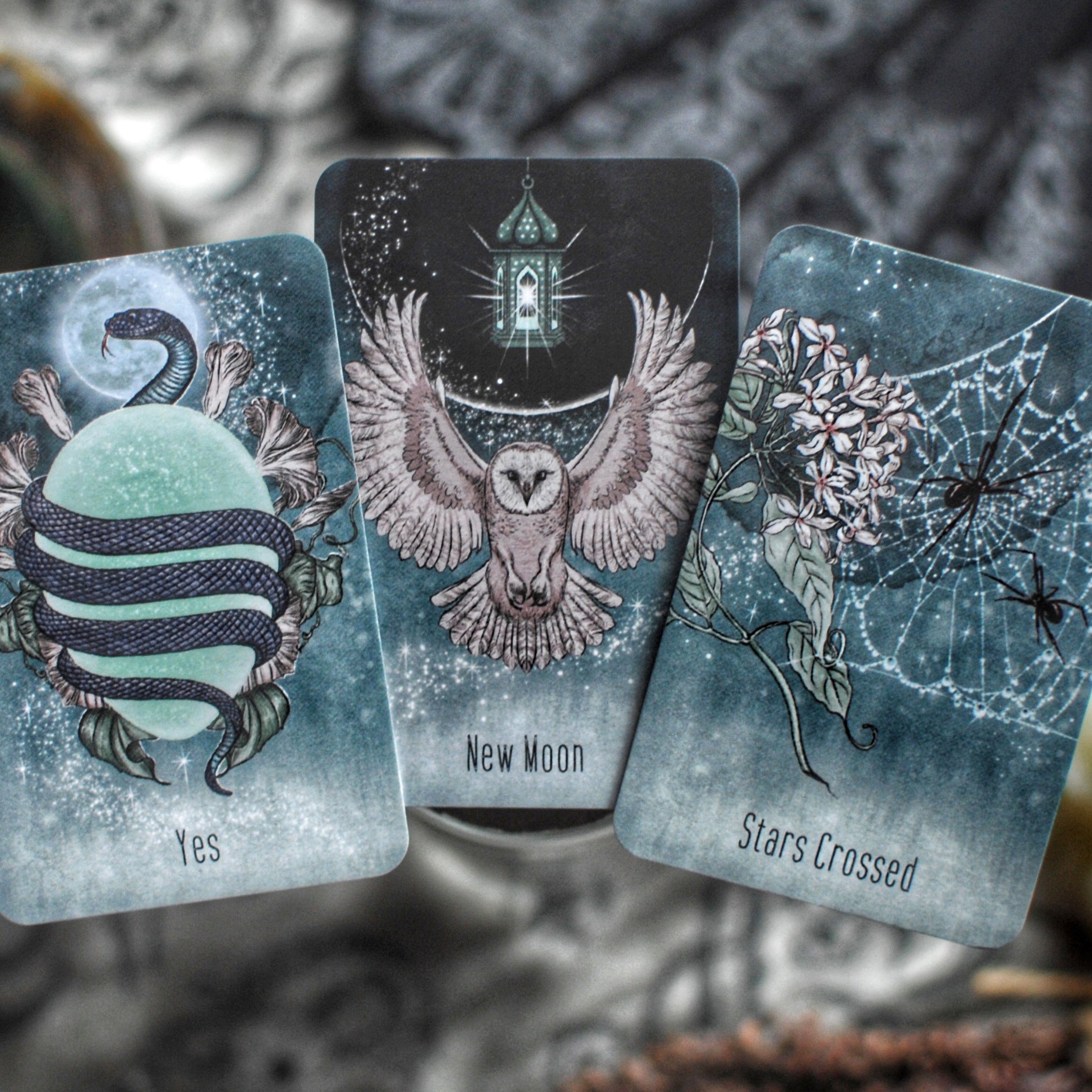 Three tarot cards with mystical designs and text on a blurred natural background